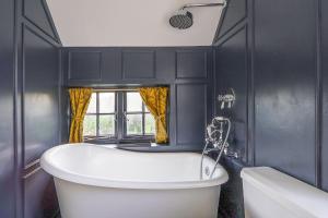 a bath tub in a bathroom with black walls at Cheerful 3 bedroom luxury house in London