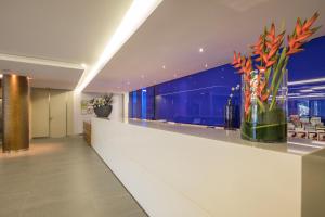 a lobby with a white counter with flowers in a vase at The Views Monumental in Funchal