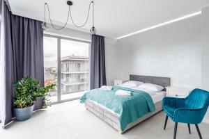a bedroom with a bed and a blue chair at Balticus Apartamenty Standard Promenada Gwiazd 14 in Międzyzdroje