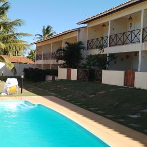 a house with a swimming pool in front of a building at Recanto Casa SOL in Barra de Jacuípe