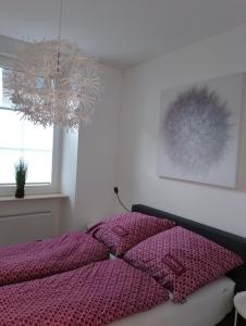 1 dormitorio con cama morada y lámpara de araña en Ferienwohnung Am Geysirzentrum, en Andernach