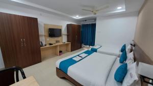 a bedroom with a large bed and a tv at The Balcony Hotel in Hyderabad