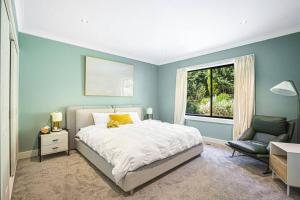 a bedroom with a bed and a chair and a window at Panoramic Mountain view house on 7ha of lands in Medlow Bath