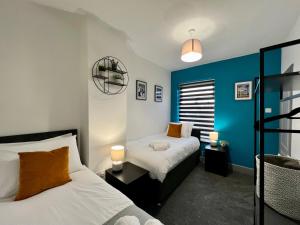 a bedroom with two beds and a blue accent wall at Bramhall House - Great for Contractors or Family Holidays in Cleethorpes