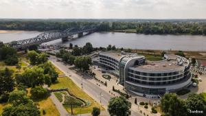 een groot gebouw naast een rivier met een brug bij Copernicus Toruń Hotel in Toruń