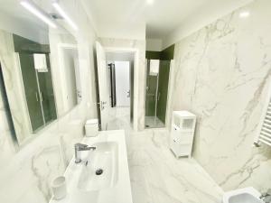 Baño blanco con lavabo y espejo en IL VIAGGIATORE RELAIS SUL MARE, en Gaeta