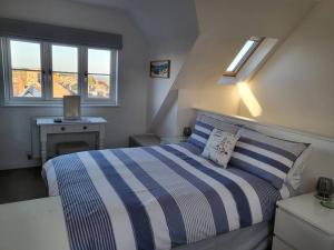 a bedroom with a blue and white bed and windows at Stones Throw-near harbour & beach Pet Friendly in Weymouth
