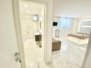 baño con suelo de mármol blanco y cama en IL VIAGGIATORE RELAIS SUL MARE, en Gaeta