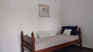 un lit en bois avec des oreillers blancs sur un mur blanc dans l'établissement Apartamento próximo aos principais pontos turísticos, à Águas de Lindóia 49 autres photos