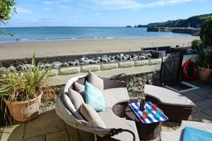 a patio with a table and chairs and a beach at Gone to the Beach - Sea Views Direct Beach Access in Saundersfoot