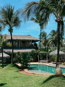 a resort with a swimming pool and palm trees at Pousada Vayú in Icaraí