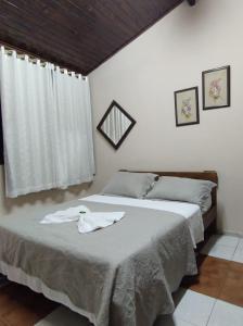 a bedroom with a bed with a white sheets and a window at Pousada Boa Vista in Brotas