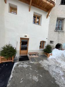 a house with a wooden door in the snow at Maison Stabatio Appartement Pierre in Le Monêtier-les-Bains
