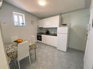 cocina con mesa, armarios blancos, mesa y sillas en RockSea Apartments Attic Floor en Cefalú