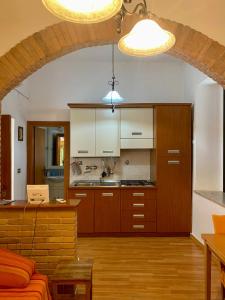 Holiday House Ginevra في فورميا: مطبخ مع دواليب خشبية وغرفة معيشة