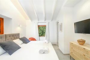 Pollensa - 35268 Mallorca في بوينسا: غرفة نوم بيضاء مع سرير كبير وتلفزيون بشاشة مسطحة