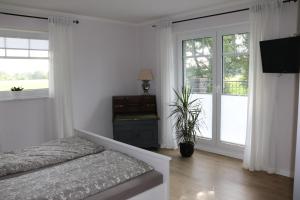 a white bedroom with a bed and a window at Ferienwohnung Am Schippstroth in Wiefelstede