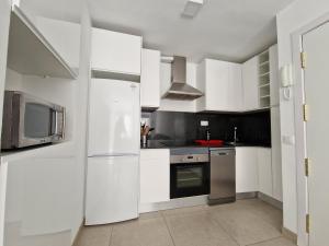 a white kitchen with a refrigerator and a microwave at La Casita de la Charca in Melenara