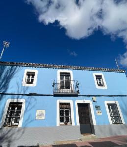 Edificio azul con 3 ventanas y balcón en Casa Rural Las Raíces, Sierra de San Vicente en San Román