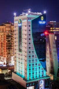 un edificio iluminado en una ciudad por la noche en Jouri a Murwab hotel Doha, en Doha