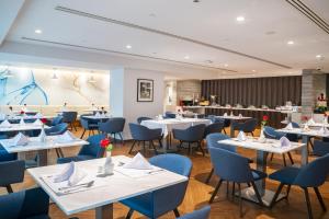 a restaurant with white tables and blue chairs at Jouri a Murwab hotel Doha in Doha