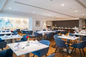 Jouri a Murwab hotel Doha في الدوحة: مطعم بطاولات بيضاء وكراسي زرقاء
