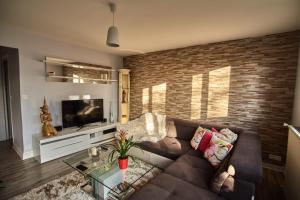 - un salon avec un canapé brun et un mur en briques dans l'établissement Chambres à louer dans appartement Balcon - wifi - parking gratuit, à Nevers