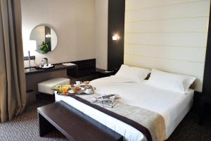 a hotel room with a bed with a tray of food on it at H2C Hotel Milanofiori in Assago