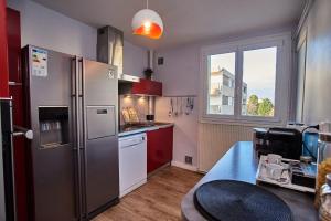 La cuisine est équipée d'un réfrigérateur en acier inoxydable et de placards rouges. dans l'établissement Chambres à louer dans appartement Balcon - wifi - parking gratuit, à Nevers