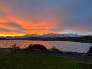 a sunset over a body of water with snow covered mountains at Loch Morar Private Suite in Mallaig