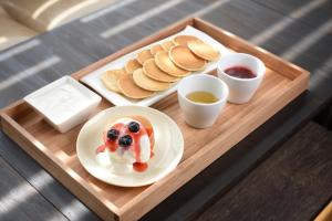 ein Tablett mit einem Teller mit Pfannkuchen und Sauce in der Unterkunft Hotel Cocktail Stay Naha in Naha