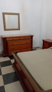 ein Schlafzimmer mit einem Bett und eine Kommode mit einem Spiegel in der Unterkunft Casa Mia Russotto 3 Sicilia in Niscemi