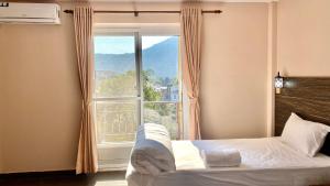 a bedroom with a bed and a large window at Hostel The Good Earth Pvt. Ltd. in Pokhara