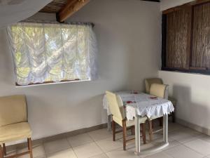 jadalnia ze stołem i krzesłami oraz oknem w obiekcie Maison bord de mer w mieście Mangalimaso