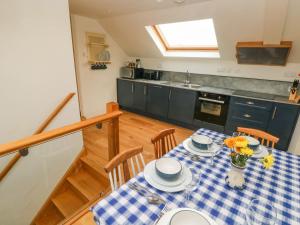 uma cozinha com uma mesa com uma toalha de mesa azul e branca em Green Grove Barn em Carmarthen