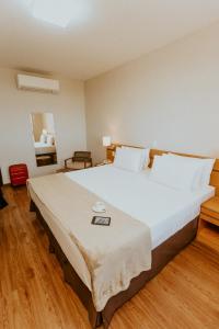 Cama blanca grande en habitación con suelo de madera en Vitoria Praia Hotel, en Vitória