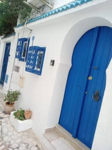 niebieskie drzwi na boku białego budynku w obiekcie Élégante Maison ' in Sidi Bou Saïd confartable, Spacieux, Central w mieście Sidi Bou Said