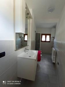 La salle de bains blanche est pourvue d'un lavabo et d'un miroir. dans l'établissement Millefiori house, à Antronapiana