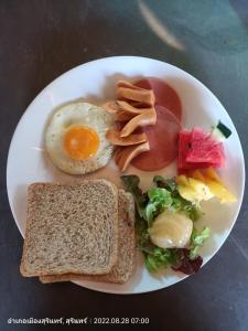 a plate of breakfast food with an egg and toast at สวนเกษตรรักษ์ไผ่ Bamboo Conservation Farm in Surin