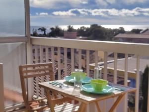 a table on a balcony with a view of the ocean at Studio Tout à Pied - Vue Sur Mer in Saint-Aygulf