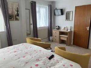 a bedroom with a bed and chairs and a television at Hayes Barton in Shanklin