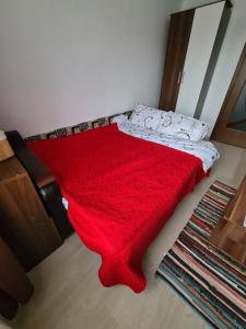 um cobertor vermelho numa cama num quarto em Vigaro Vgr em Brasov