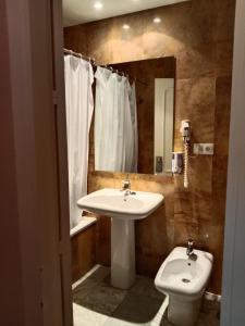 W łazience znajduje się umywalka, toaleta i lustro. w obiekcie Hotel Trafalgar w mieście Jerez de la Frontera