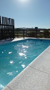 una piscina con agua azul y una valla de madera en Casa Ruca Maná, en Sierra de la Ventana