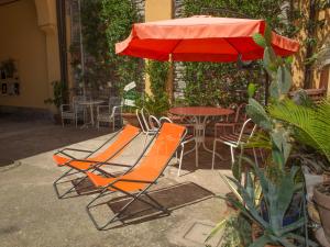einen Regenschirm, zwei Stühle und einen Tisch mit Sonnenschirm in der Unterkunft La Corte di Zizi in Cernobbio
