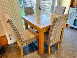 a wooden table with three chairs and a kitchen at Stunning Beach Front house - Sleeps 6 in Pwllheli