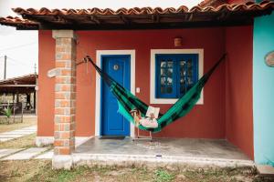 a person in a hammock in front of a house at Vila Capininga Ecopousada in Santo Amaro