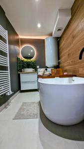 ein Bad mit einer großen weißen Badewanne in einem Zimmer in der Unterkunft Le Petit Bali in Sélestat