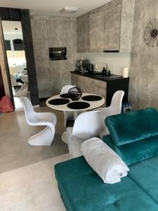 ein Wohnzimmer mit einem Tisch und einigen weißen Stühlen in der Unterkunft Apartament Na Wydmie in Ustka