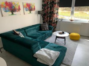 ein Wohnzimmer mit einem grünen Sofa und einem Tisch in der Unterkunft Apartament Na Wydmie in Ustka